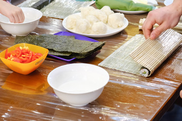 Fototapeta premium Cooking of traditional sushi rolls. The boy is dressed as a cook.