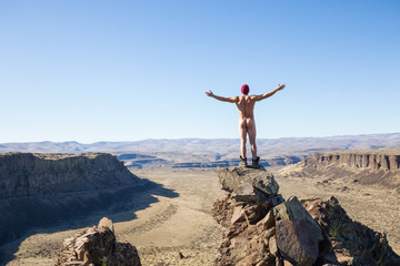 Naked man standing on top of a mountain peak overlooking the valley. Taken in Frenchman Coulee, Vantage, Washington, America.