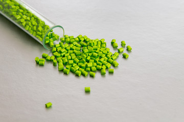 Plastic pellets . Plastic raw materials in granules for industry.Green Polymeric dye on a silver...