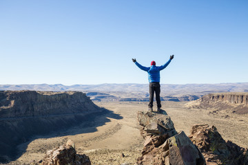 Obraz premium Naked man standing on top of a mountain peak overlooking the valley. Taken in Frenchman Coulee, Vantage, Washington, America.
