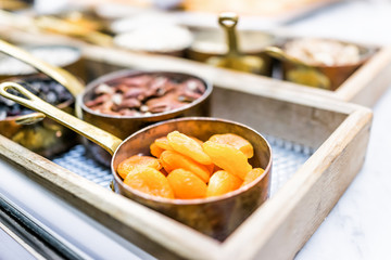 Macro closeup of wooden tray with bowls of dried apricots, fruit, nuts in kitchen counter cooking measurement portions sweet