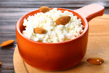 Homemade cottage cheese with almonds and raisins in a bowl on a wooden table.