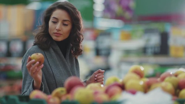 Portrait young woman choosing apple fruit vegetable supermarket light marketplace lifestyle commerce product fresh hand customer food beautiful girl shopping selecting face buy store grocery holding
