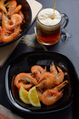 Shrimp in a black plate with a glass of beer