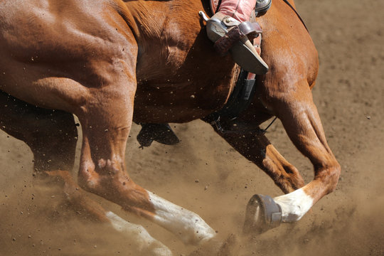 A close up view of a horse running in the dirt kicking up dust in a barrel race.
