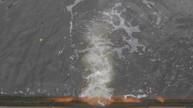 Industrial pipe discharging liquid waste in a clean river.