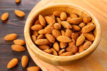 Raw dry nuts of almonds in a wooden bowl on a wooden table.