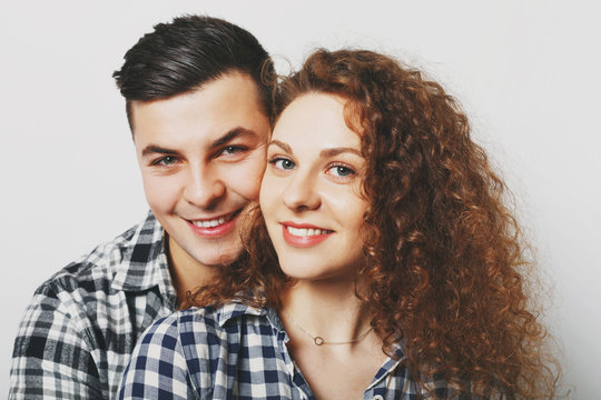 Close up of lovely family couple cuddle and look cheerfully at camera, celebrate their wedding anniversary, wear checkered shirts, isolated over white background. People, love and family concept