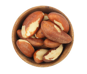 Brazil nuts in wooden bowl isolated on white background closeup. Top view. Flat lay