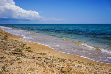 Sand and shell beach of the sea in the Crimea on the background of bright blue sea and clear sky