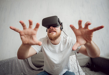 Naklejka premium The young man playing games with virtual reality goggles