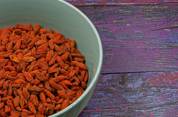 Bowl of dry Goji berries on wooden background