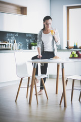 Happy woman drinking tea in the kitchen at home