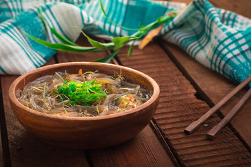 Japanese cuisine, soup with chashu pork, chives, sprouts, noodles and seaweed on the table under the sunlight. Wooden rustic background. Top view