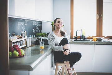 Young woman sitting a table in the kitchen .