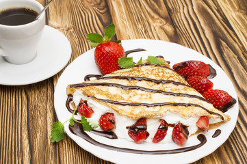 Crepes with Banana and strawberries on a wooden background, pancakes.