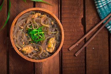 Obraz na płótnie Canvas Japanese cuisine, soup with chashu pork, chives, sprouts, noodles and seaweed on the table under the sunlight. Wooden rustic background. Top view