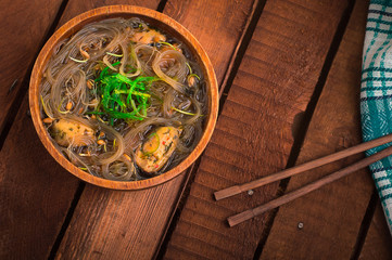 Japanese cuisine, soup with chashu pork, chives, sprouts, noodles and seaweed on the table under the sunlight. Wooden rustic background. Top view