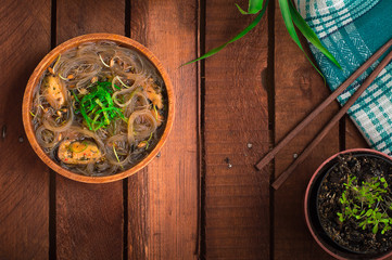 Japanese cuisine, soup with chashu pork, chives, sprouts, noodles and seaweed on the table under the sunlight. Wooden rustic background. Top view