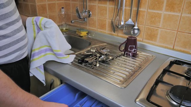 A man wiping cutlery in the kitchen