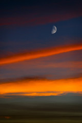 Luna en cuarto menguante se destaca sobre el cielo al atardecer.