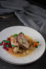 Pork ribs with beets, carrots, fried mushrooms and sauce on a white plate. Restaurant serving. Old black rustic background. Top view