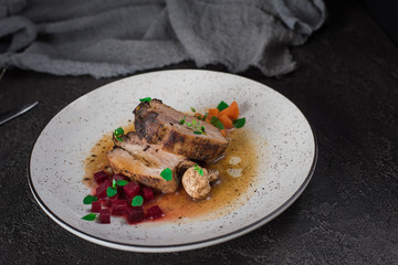 Pork ribs with beets, carrots, fried mushrooms and sauce on a white plate. Restaurant serving. Old black rustic background. Top view
