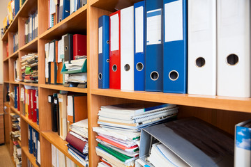 Row of colorful office folders with blank white labels on shelf
