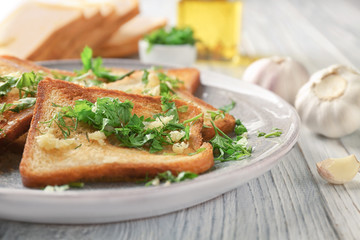 Plate with delicious homemade garlic bread on table