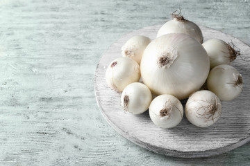 Ripe onions on white wooden background