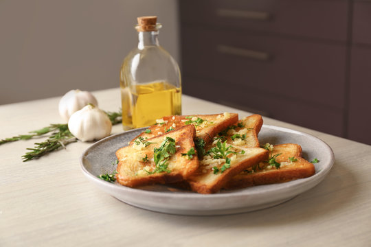 Plate with delicious homemade garlic bread on table
