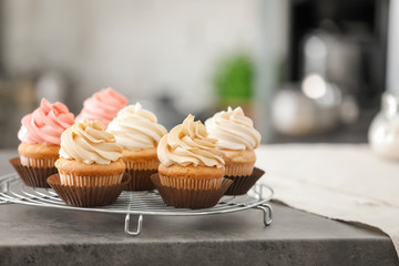 Cooling rack with tasty cupcakes on table