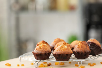 Cooling rack with tasty cupcakes on table