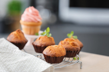 Cooling rack with tasty cupcakes on table