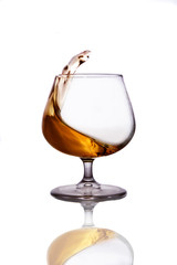 Splash of cognac in glass isolated on white background