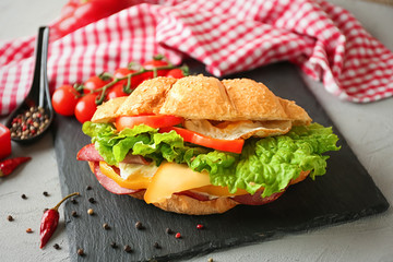Tasty croissant sandwich on slate plate