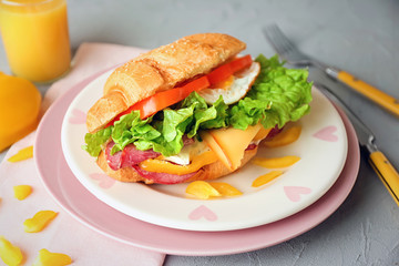 Plate with tasty croissant sandwich on table