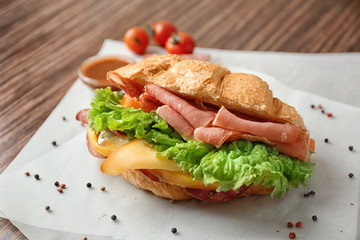 Tasty croissant sandwich on table