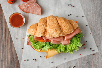 Tasty croissant sandwich on table