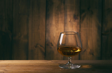 Glass of cognac on the wooden table.