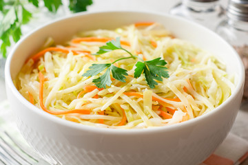 Fresh coleslaw salad in bowl on gray stone background.