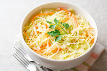 Fresh coleslaw salad in bowl on gray stone background.