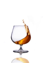 Splash of cognac in glass isolated on white background 