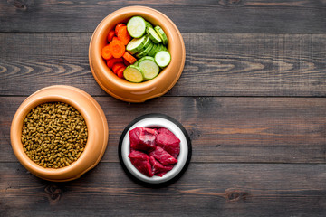 Ingredients for dry pet food. Meat and vegetables zucchini and carrot on dark wooden backgroud top view copy space