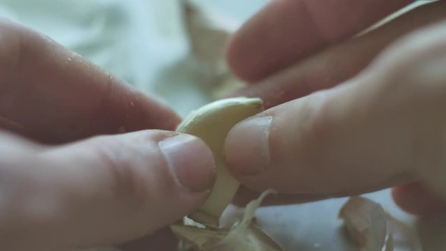 man is cleaning garlic close-up cloves. Vegetarians garlic food in indoors the kitchen lifestyle