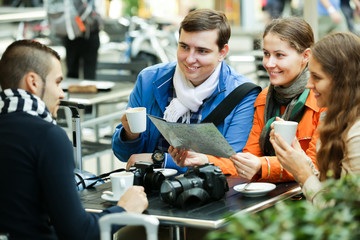 Tourists drinking coffee at cafe and reading city map