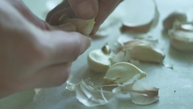 man is cleaning garlic close-up cloves. Vegetarians garlic food indoors in the kitchen lifestyle