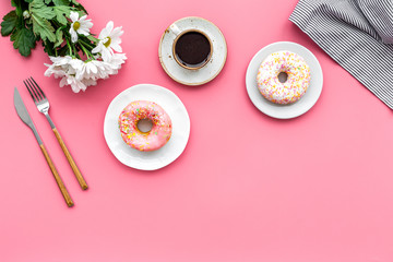 breakfast with coffee, donuts and flowers on pink background top view mockup