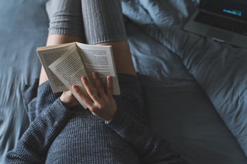 Fototapeta premium woman read book in bed. laptop on background.