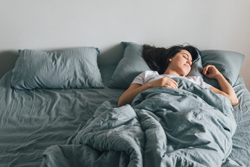 Fototapeta na wymiar woman sleep in bed with gray sheets. happy morning concept